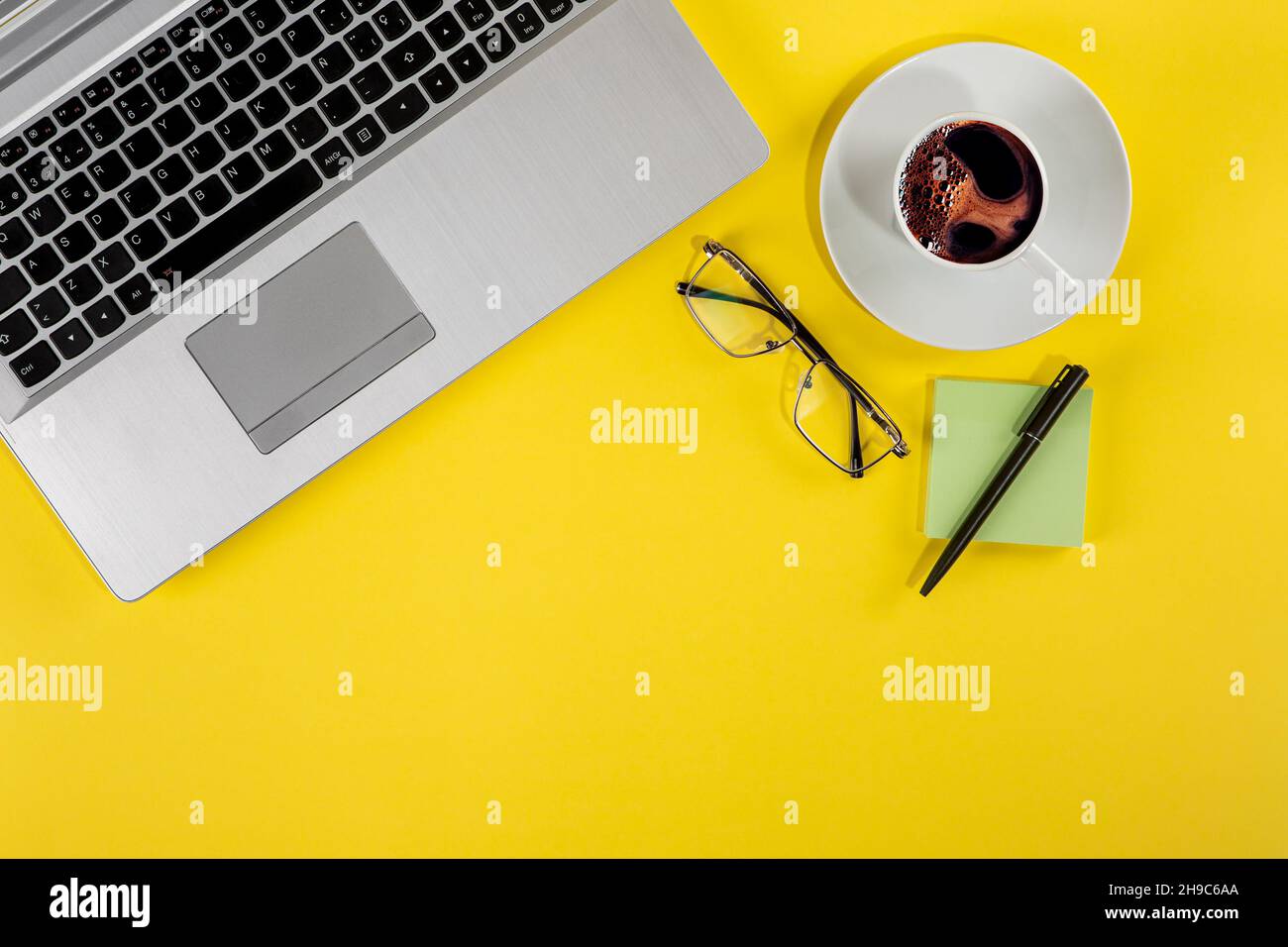 Vue de dessus photo studio d'un ordinateur portable, d'une tasse de café et d'éléments fixes sur fond jaune Banque D'Images
