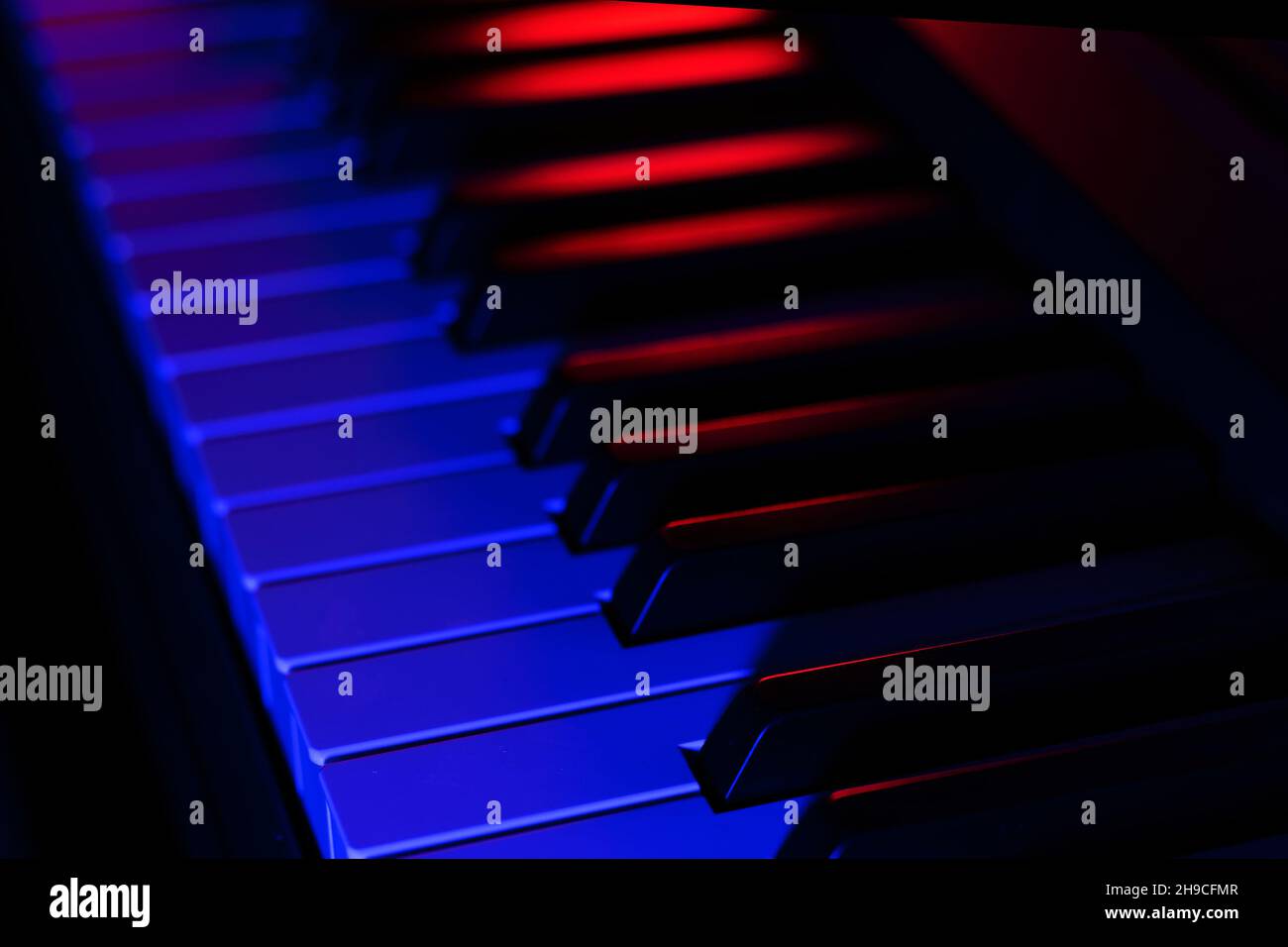 Clés de piano dans la boîte de nuit ou au bar en gros plan.L'instrument de musique est éclairé par une lumière colorée dans un cabaret ou un restaurant.Arrière-plan sombre. Banque D'Images