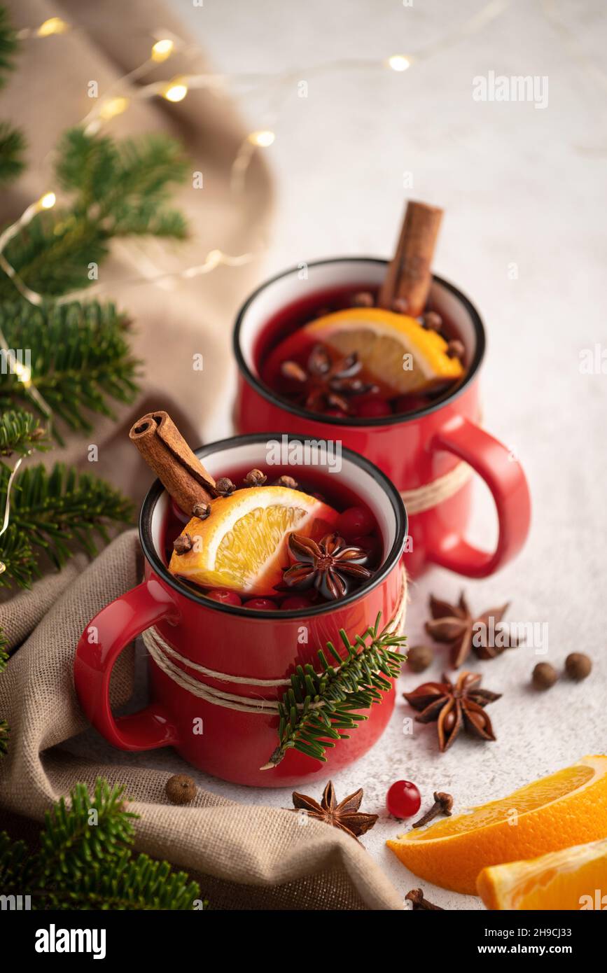Deux tasses de vin chaud avec des quartiers d'orange et des épices entourées d'un décor de Noël Banque D'Images