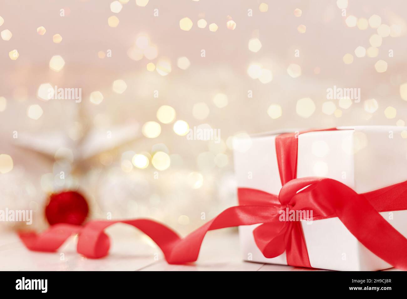 Arrière-plan de Noël ou du nouvel an.Coffret cadeau blanc avec ruban rouge et décoration de noël avec lumières bokeh en arrière-plan.Ventes et achats de vacances Banque D'Images