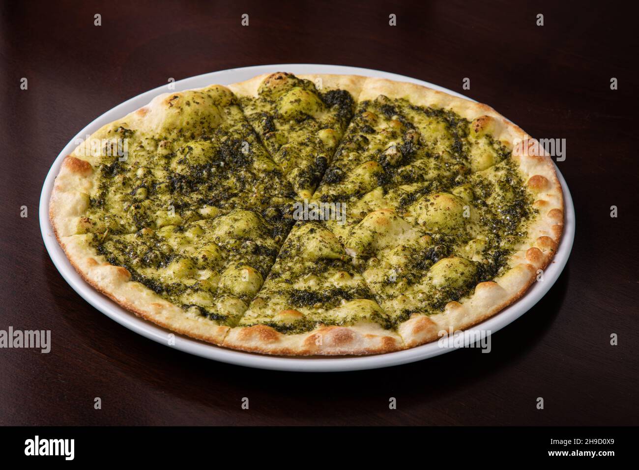 Focaccia au fromage et pesto sur un plat blanc sur une table en bois sombre Banque D'Images