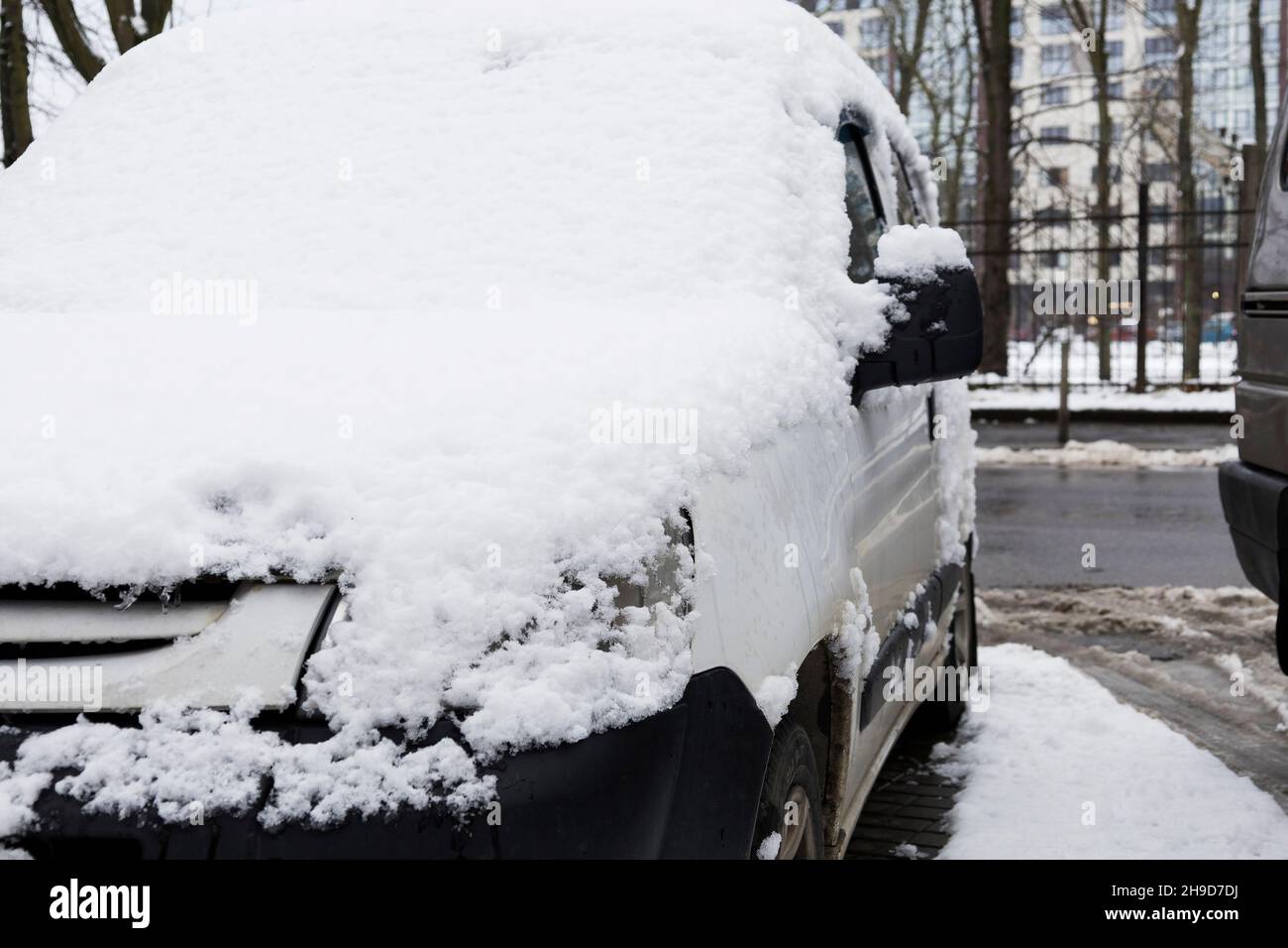 La voiture est dans une chasse-neige près de la maison.La voiture de tourisme était recouverte de neige.Il y a beaucoup de neige dehors. Banque D'Images