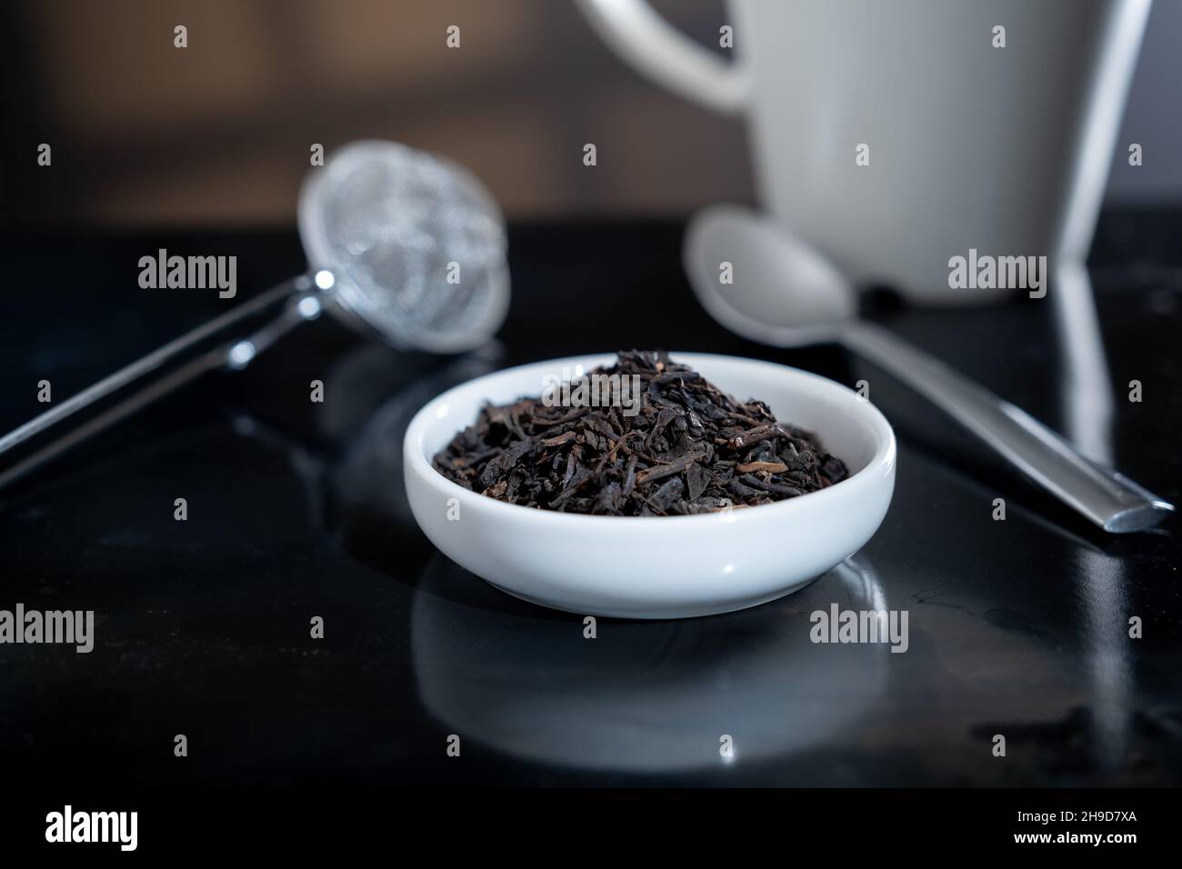 Helsinki / Finlande - 4 DÉCEMBRE 2021 : gros plan sélectif d'une tasse remplie de feuilles de thé fraîches.Un filtre à thé hors foyer en arrière-plan. Banque D'Images