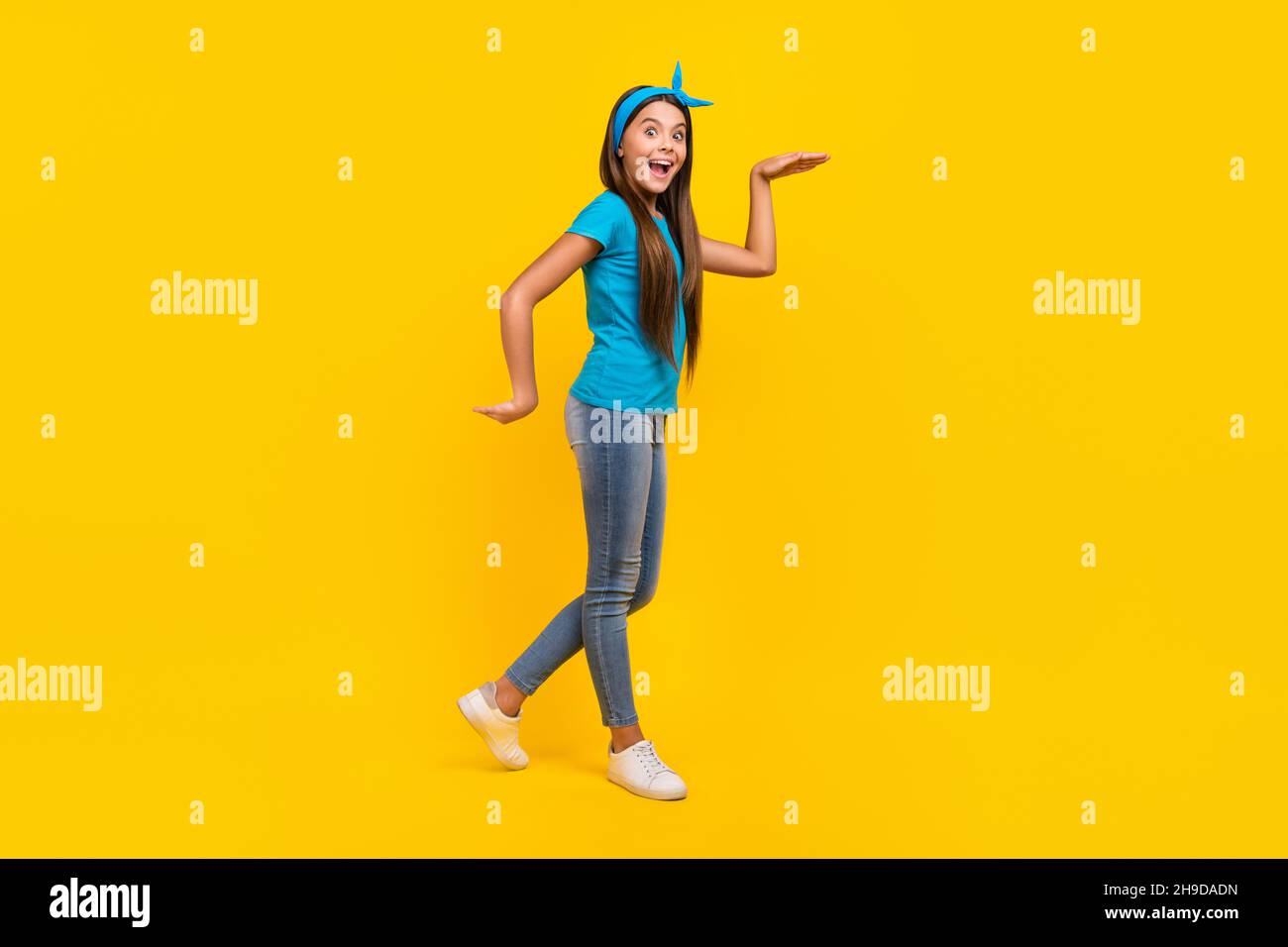 Photo de côté pleine profil de corps de jeune charmante dame ont amusant marche danseuse ludique isolée sur fond jaune de couleur Banque D'Images