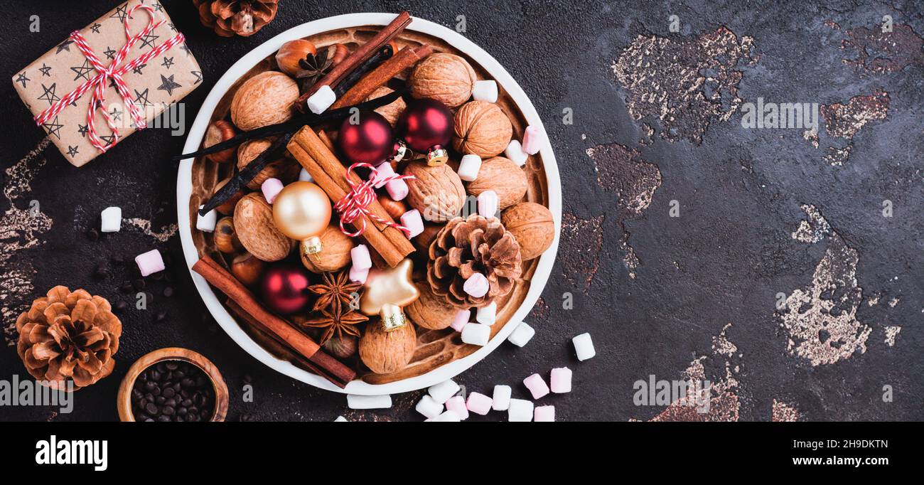 Noix et épices de noël dans un bol en céramique sur fond d'ardoise sombre, de pierre ou de métal.Expérience culinaire avec des ingrédients pour cuire des biscuits au chocolat Banque D'Images