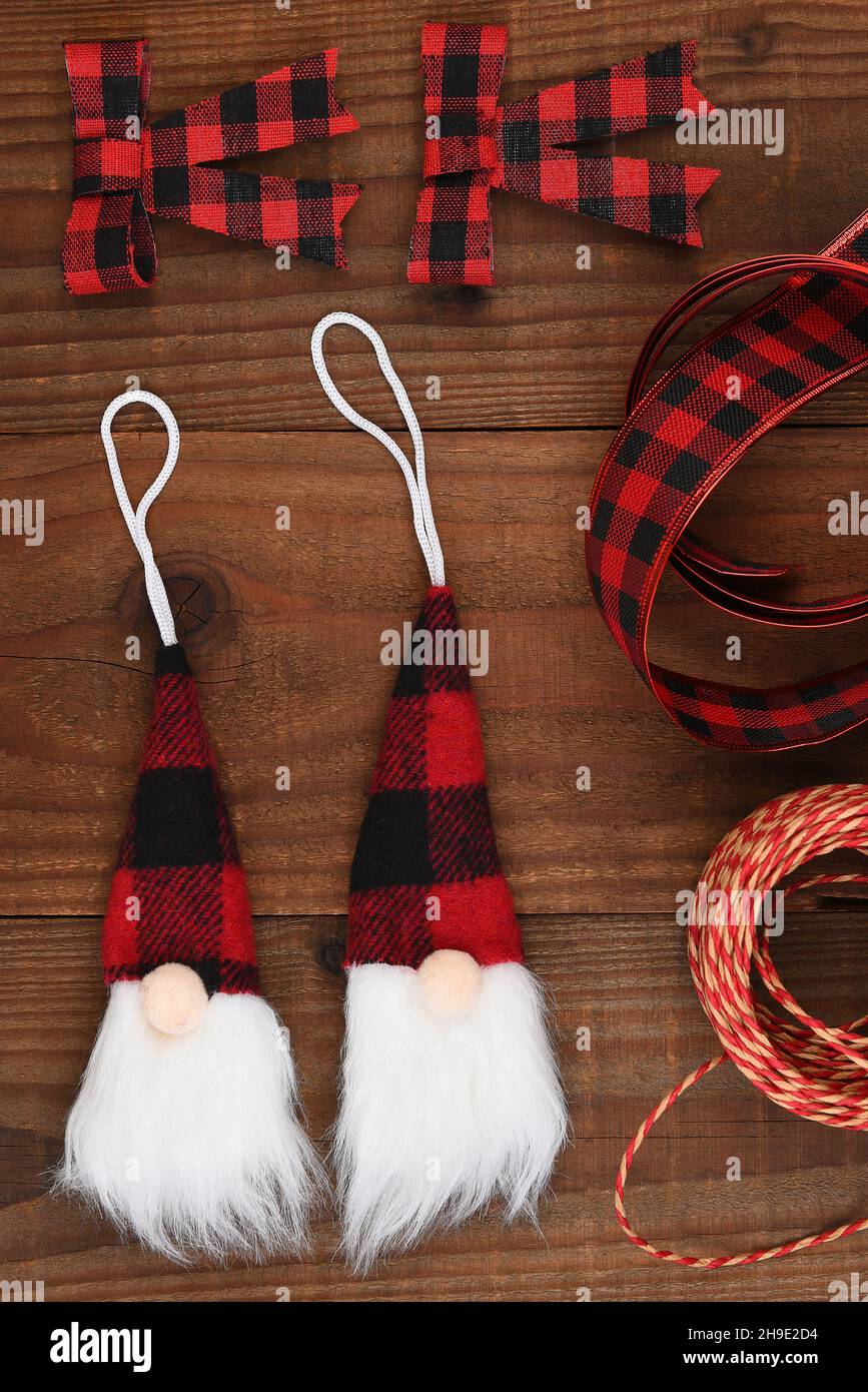 Plat de Noël - un arrangement d'ornements de Gnome et d'arcs en tissu noir et rouge avec ruban et ficelle. Banque D'Images