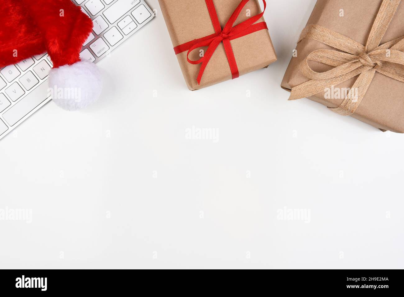 Concept de Noël à plat.Un clavier d'ordinateur avec Santa Hat et deux papier ordinaire emballé présente et espace de copie dans la moitié inférieure de l'image. Banque D'Images