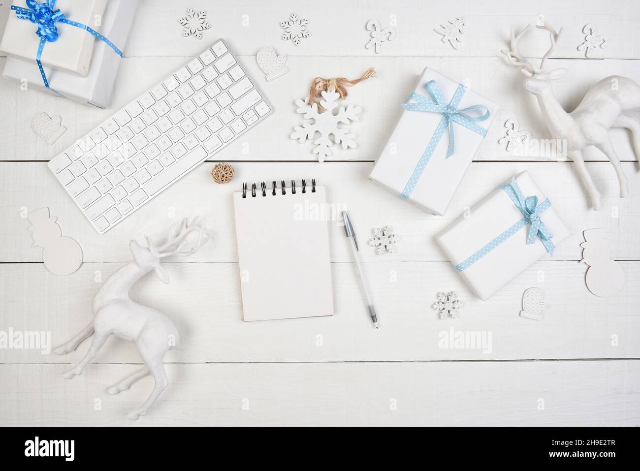 Concept de Noël à plat.Papier blanc emballé présente avec ruban bleu un bloc-notes vierge et un clavier d'ordinateur pour cyber-shopping. Banque D'Images