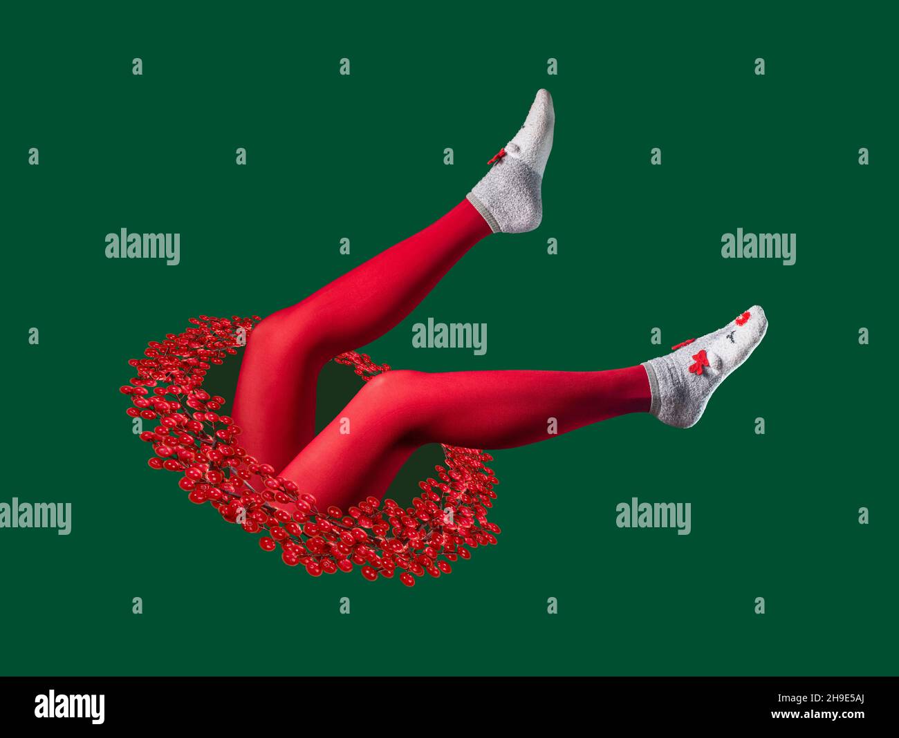 Collage surréaliste de Noël avec jambes de femme en collants rouges et chaussettes chaudes d'hiver avec oreilles de renne tombantes dans un trou magique avec couronne de Noël. Banque D'Images
