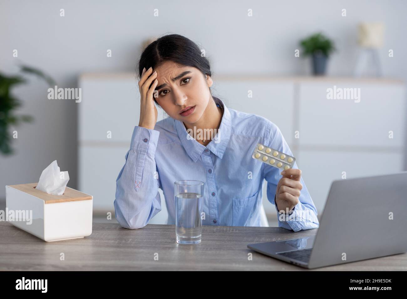 Malheureux bouleversé jeune femme indienne malade, souffrant de maux de tête, de rhumes et de grippe contient des pilules à l'intérieur du bureau Banque D'Images