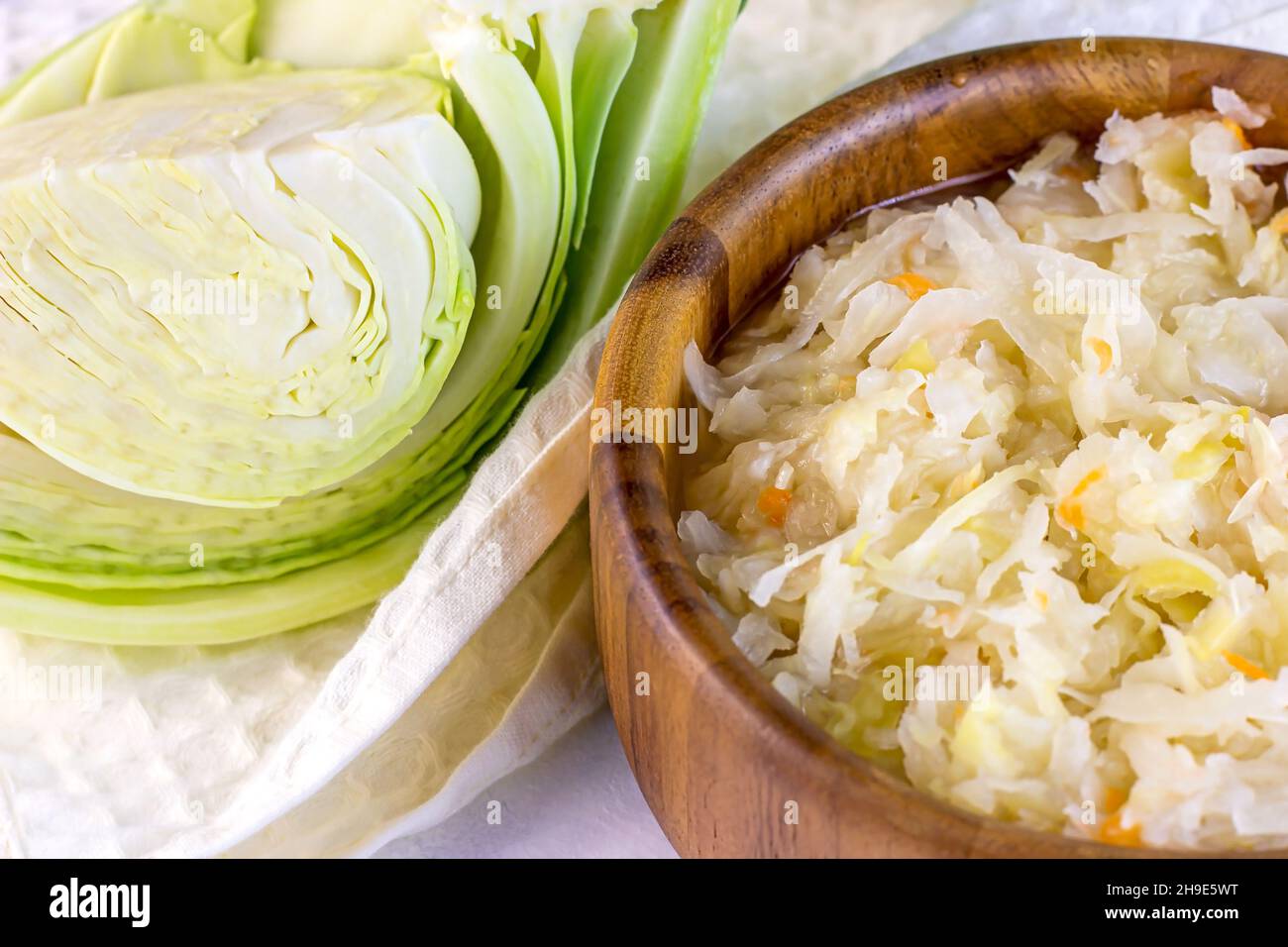 Bol rond en bois brun avec une choucroute savoureuse de chou râpé et de carottes sur fond blanc. Banque D'Images
