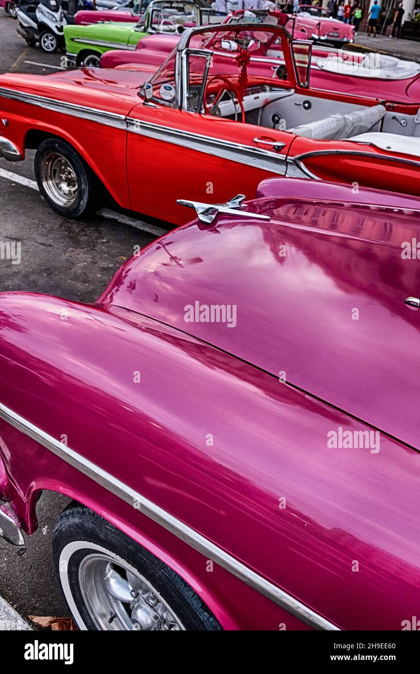 Une gamme de voitures américaines classiques peintes dans des couleurs vives qui sont disponibles à la location dans la vieille ville de la Havane. Banque D'Images