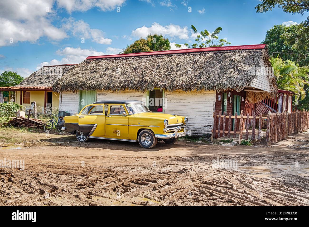 Une voiture jaune d'époque jaune d'Amérique travaillant comme un taxi attend pour un trajet devant un restaurant cubain local dans la ville de Vinales. Banque D'Images