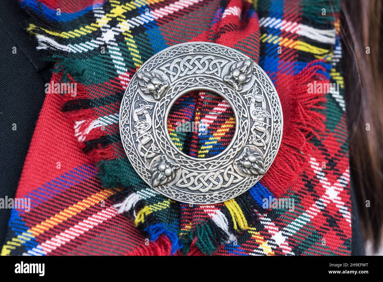 Détail d'un écusson sur une barre en tissu écossais tartan d'une tenue traditionnelle des Highlands Scots. Banque D'Images