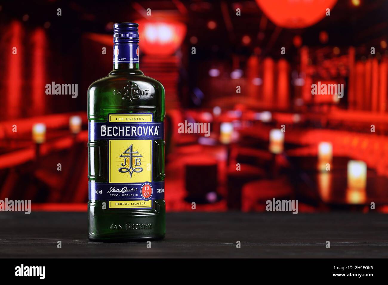 KHARKOV, UKRAINE - 14 FÉVRIER 2021 : bouteille de liqueur à base de plantes Becherovka sur table en bois avec intérieur de barre rouge sur fond.Production d'alcool élite Banque D'Images