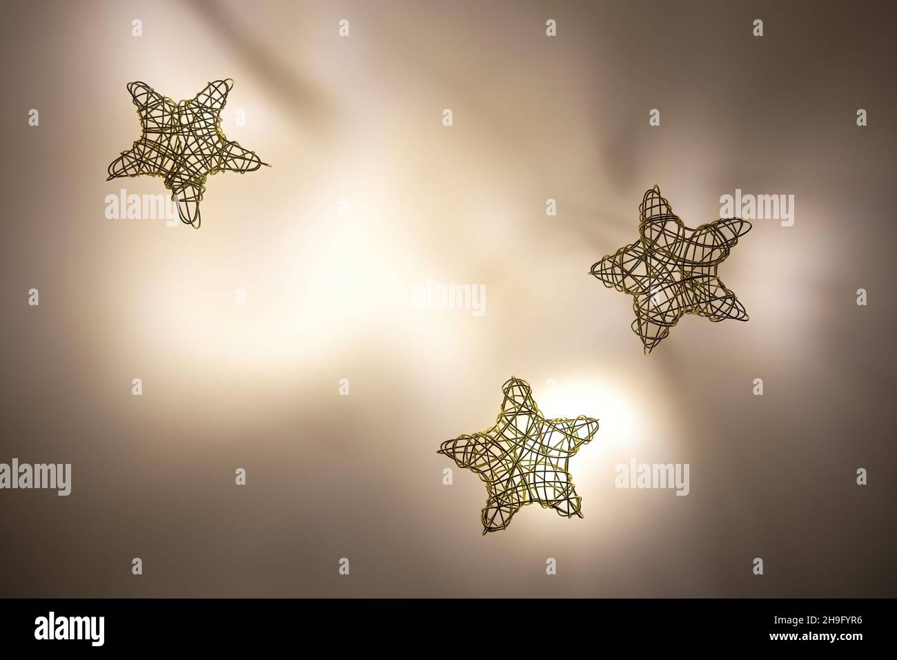 trois étoiles tissées en fil d'or sur fond éclairé Banque D'Images