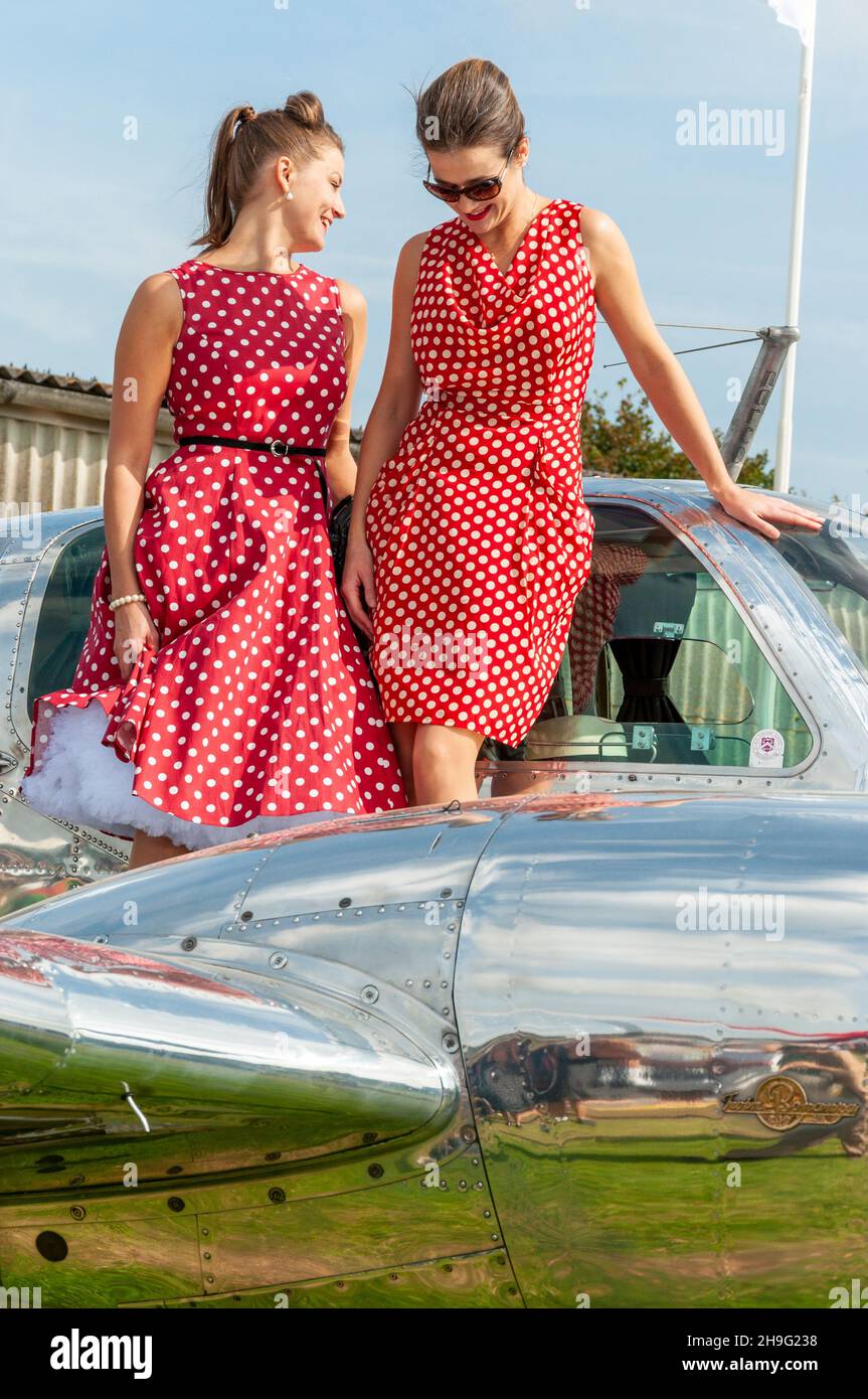 Femmes en costume d'époque, robes à pois années soixante, posant sur un avion classique au Goodwood Revival 2014.mode 1950s ou 1960s Banque D'Images