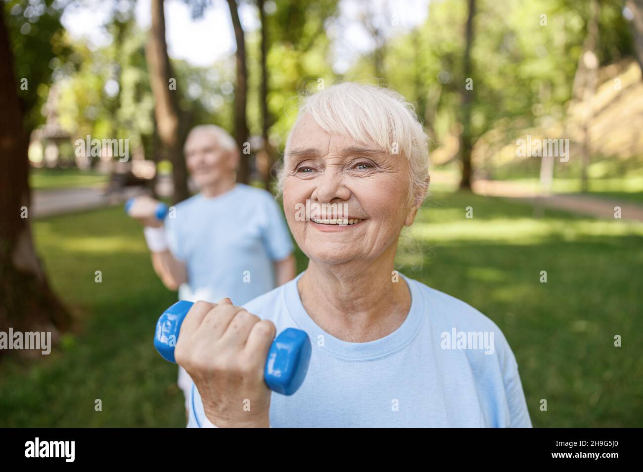 Bonne dame senior fait des exercices avec entraînement de haltères avec partenaire dans le parc Banque D'Images