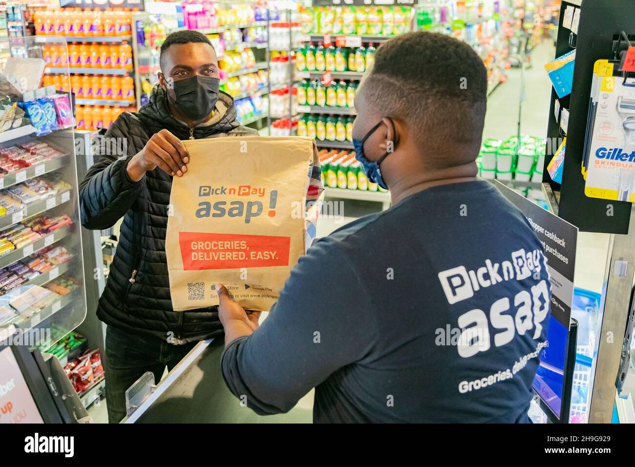 Cape Town, Afrique du Sud - 9 septembre 2021 : le livreur Express Service collecte la commande auprès du personnel au comptoir à l'intérieur de l'épicerie locale Pick n Pay Banque D'Images