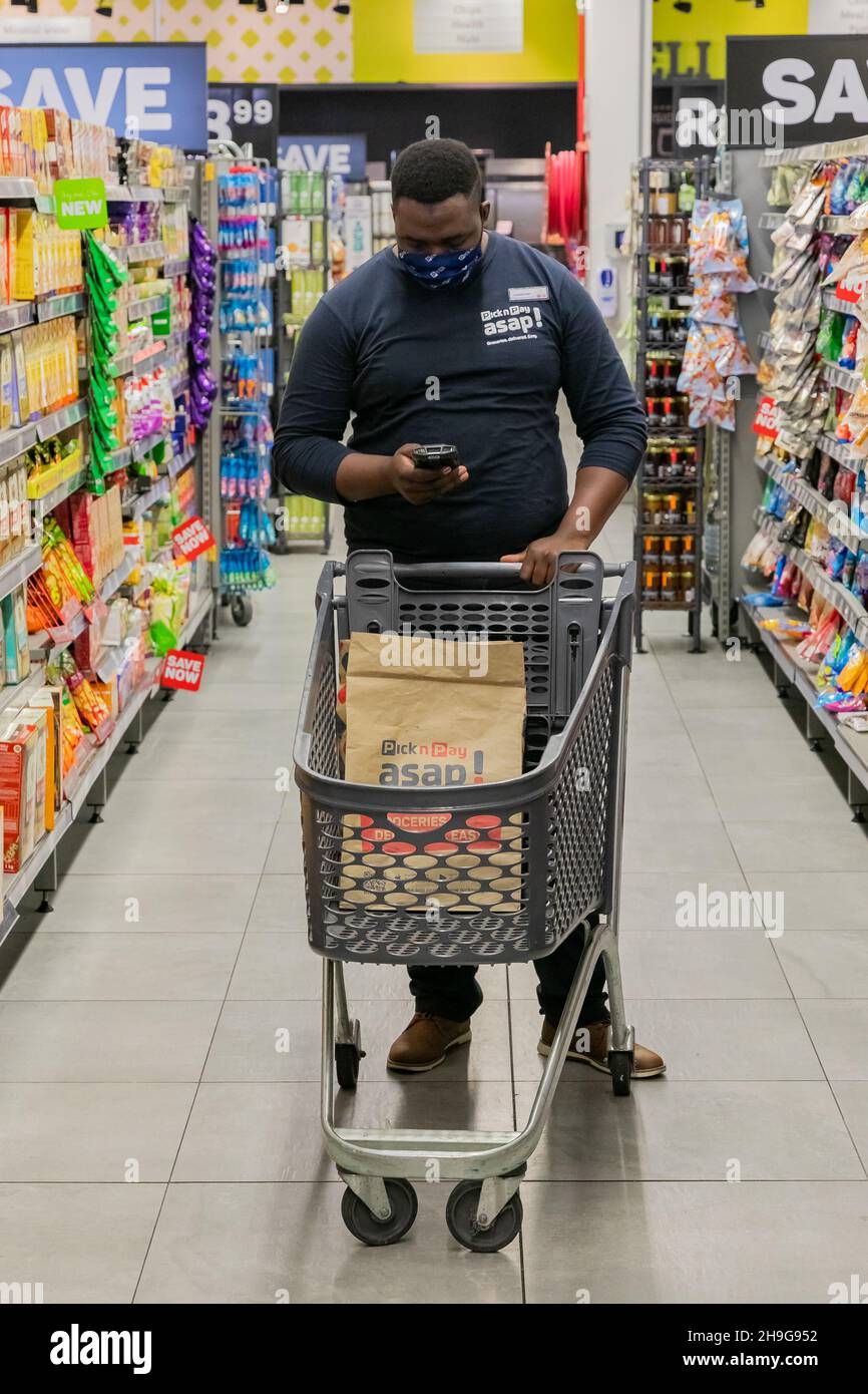 Cape Town, Afrique du Sud - 9 septembre 2021 : un membre du personnel cueille des produits à partir de l'étagère pour un service de livraison express à domicile Banque D'Images