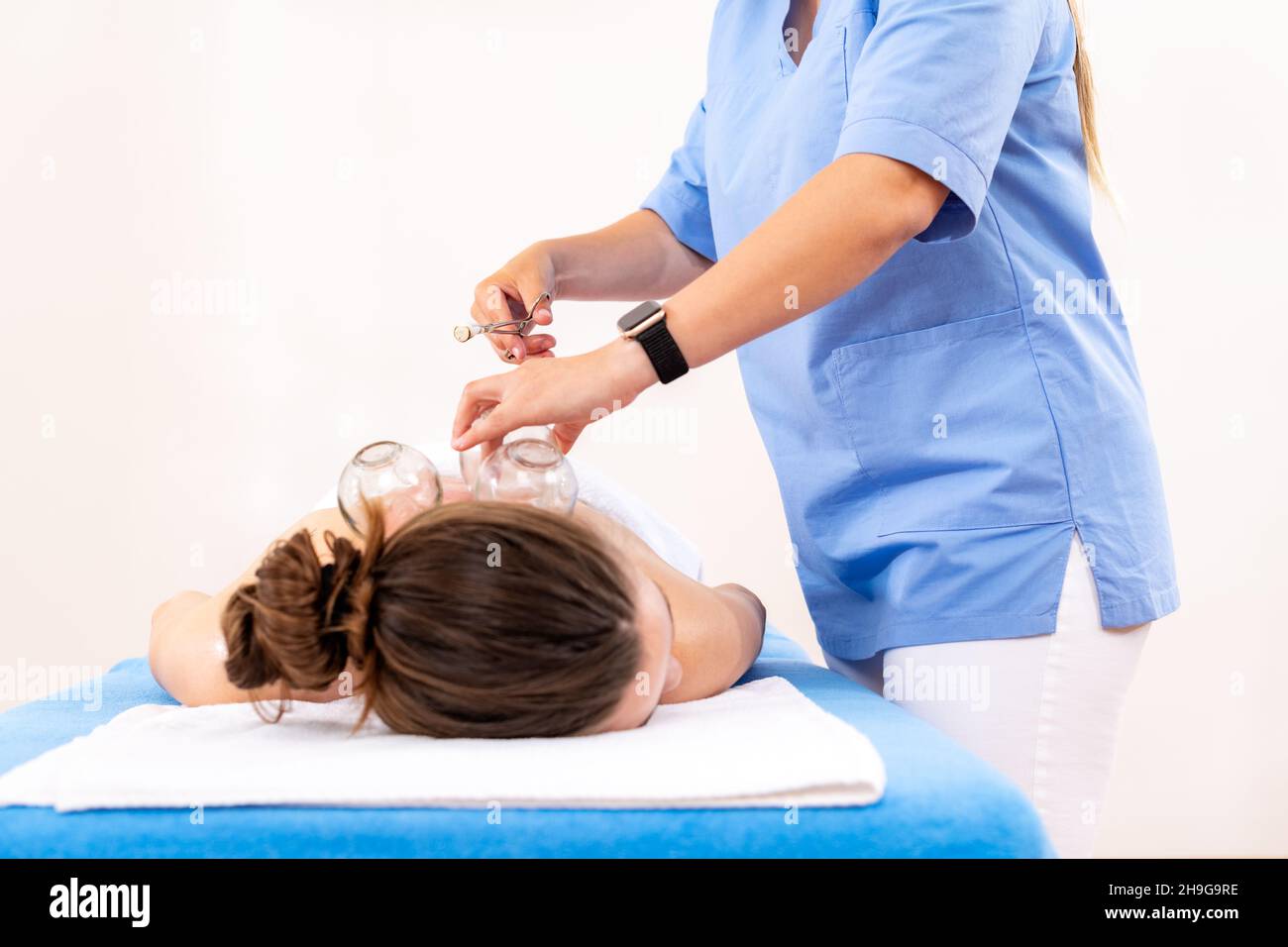 Arrière-plan de la cupthérapie sous vide.Une jeune physiothérapeute femme applique des ventouses sur le dos de sa patiente, pour soulager les douleurs musculaires. Banque D'Images