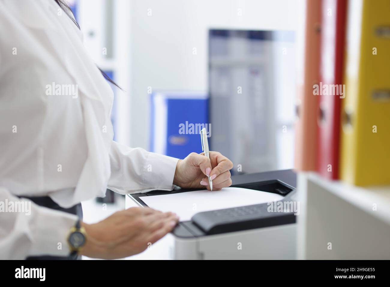 Une femme secrétaire ou employée de bureau imprime des papiers sur une imprimante Banque D'Images