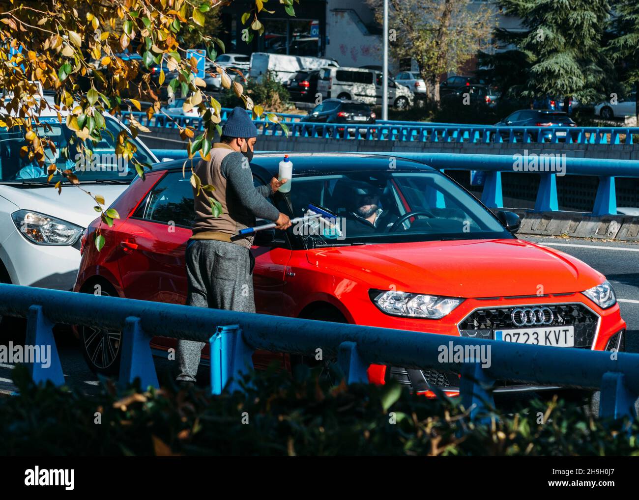 Homme d'âge moyen d'apparence sud-asiatique travaillant par lavage des vitres de voiture avec un essuie-glace (raclette) à Madrid, Espagne.Autoroute M30 Banque D'Images Homme d'âge moyen d'apparence sud-asiatique travaillant par lavage des vitres de voiture avec un essuie-glace (raclette) à Madrid, Espagne.Autoroute M30 Banque D'Images