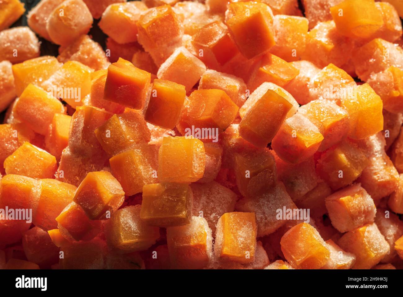 Des morceaux de cube de carottes fraîches surgelées ferment l'arrière-plan Banque D'Images