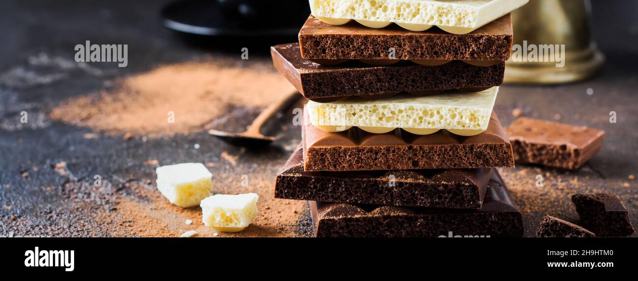 Mélanger la pile de chocolat noir poreux amer, laiteux et blanc sur fond ancien sombre.Mise au point sélective. Banque D'Images