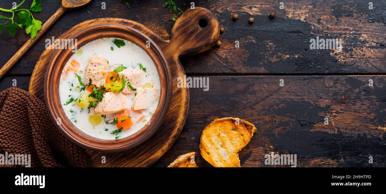 Soupe crémeuse finlandaise chaude avec saumon et légumes dans un ancien bol en céramique sur fond de bois ancien.Style rustique.Vue de dessus. Banque D'Images