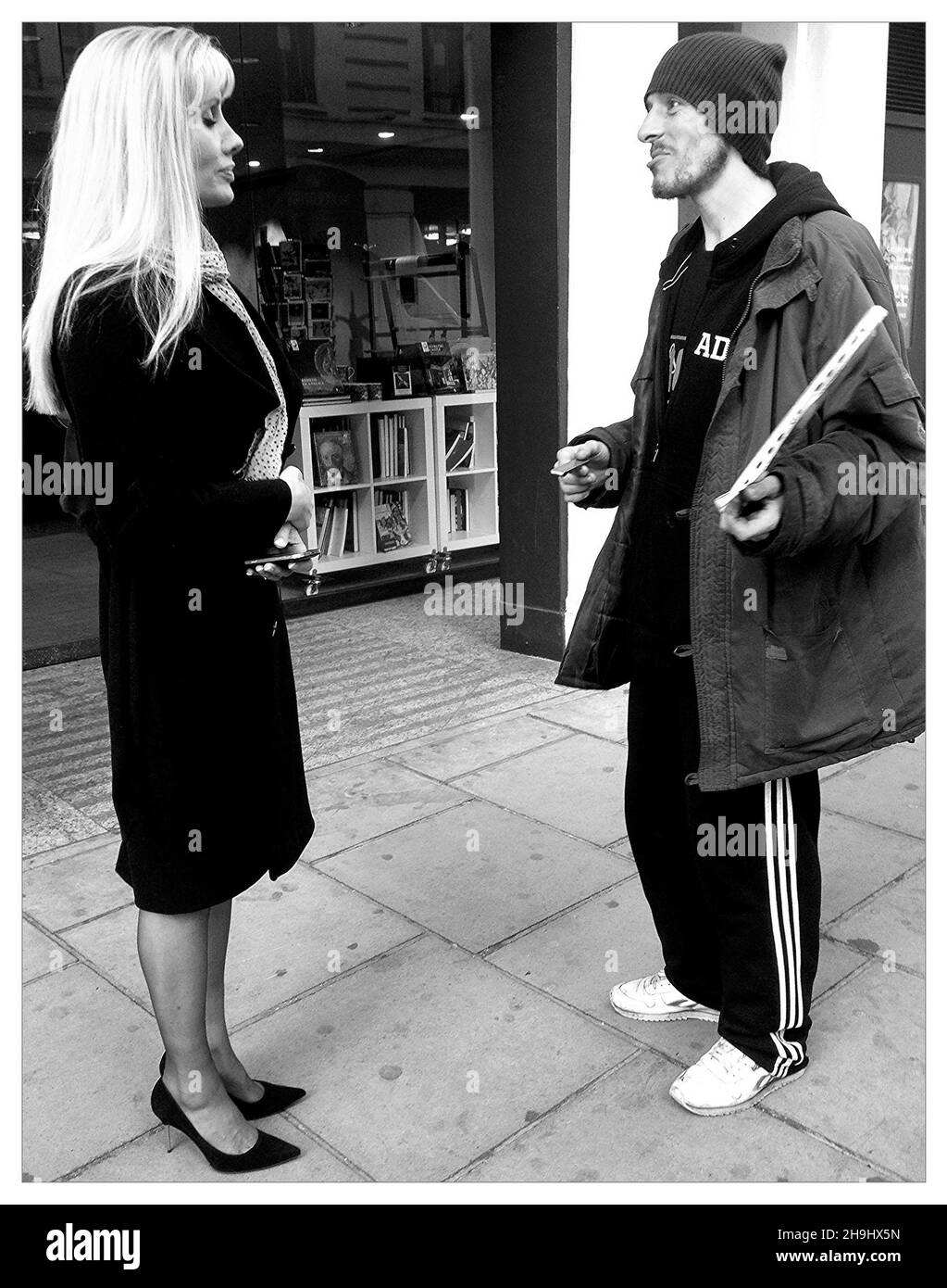 Un fournisseur de gros problèmes qui parle à un passant à Kensington, Londres (une image traitée avec l'application mobile Flickr dans le cadre d'une série d'images expérimentales prises et traitées sur l'iPhone) Banque D'Images