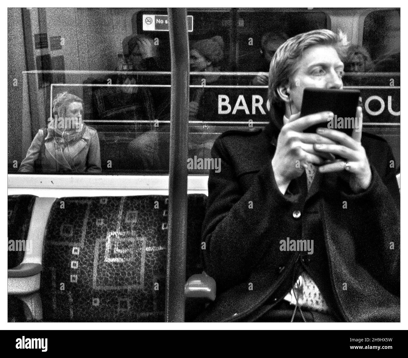 Un itinérant sur le métro de Londres lisant un Kindle (une image traitée à l'aide de la nouvelle application mobile Flickr dans le cadre d'une série d'images expérimentales prises et traitées sur l'iPhone) Banque D'Images