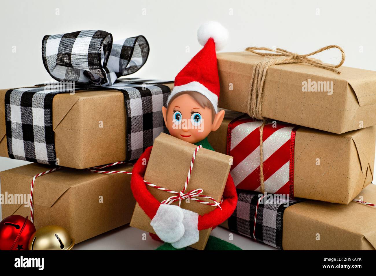 Gros plan d'un Elf de Noël assis dans une pile de boîtes-cadeaux esprit de Noël, la tradition familiale de Noël. Banque D'Images