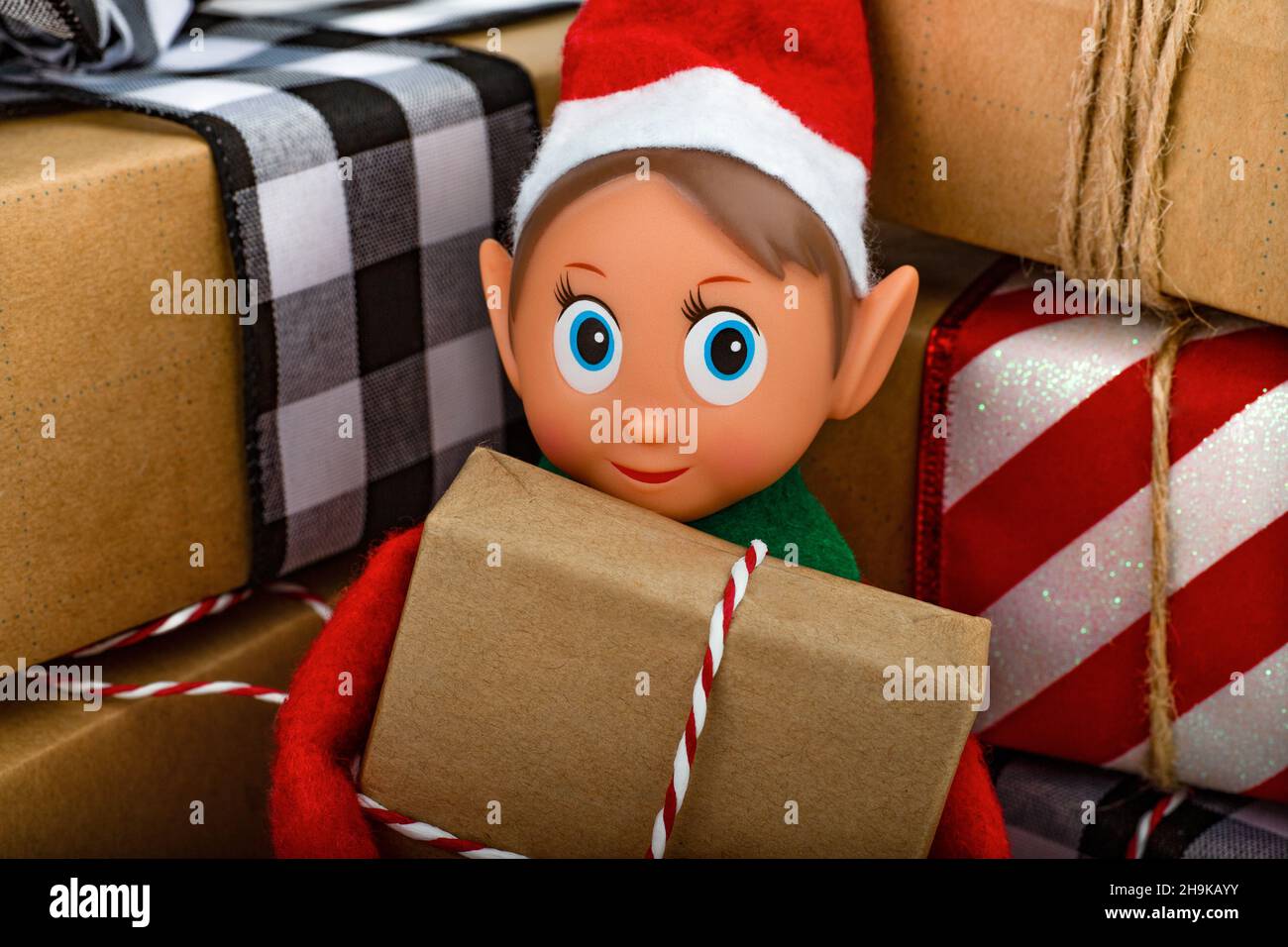 Gros plan d'un Elf de Noël assis dans une pile de boîtes-cadeaux esprit de Noël, la tradition familiale de Noël. Banque D'Images