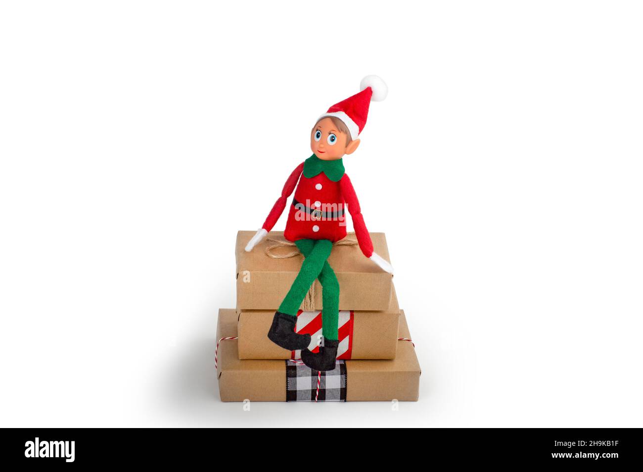 Elf de Noël assis sur une pile de boîtes-cadeaux sur un fond blanc isolé avec espace de copie.L'esprit de Noël, la tradition familiale de Noël. Banque D'Images
