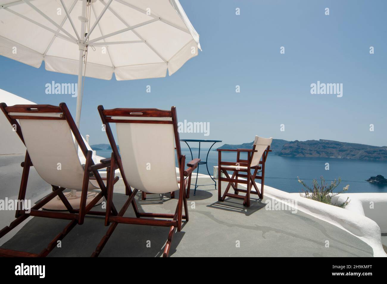 Terrasse panoramique avec vue sur la caldeira à Oia, Grèce.Parasol et chaises longues pour une détente totale en vacances Banque D'Images