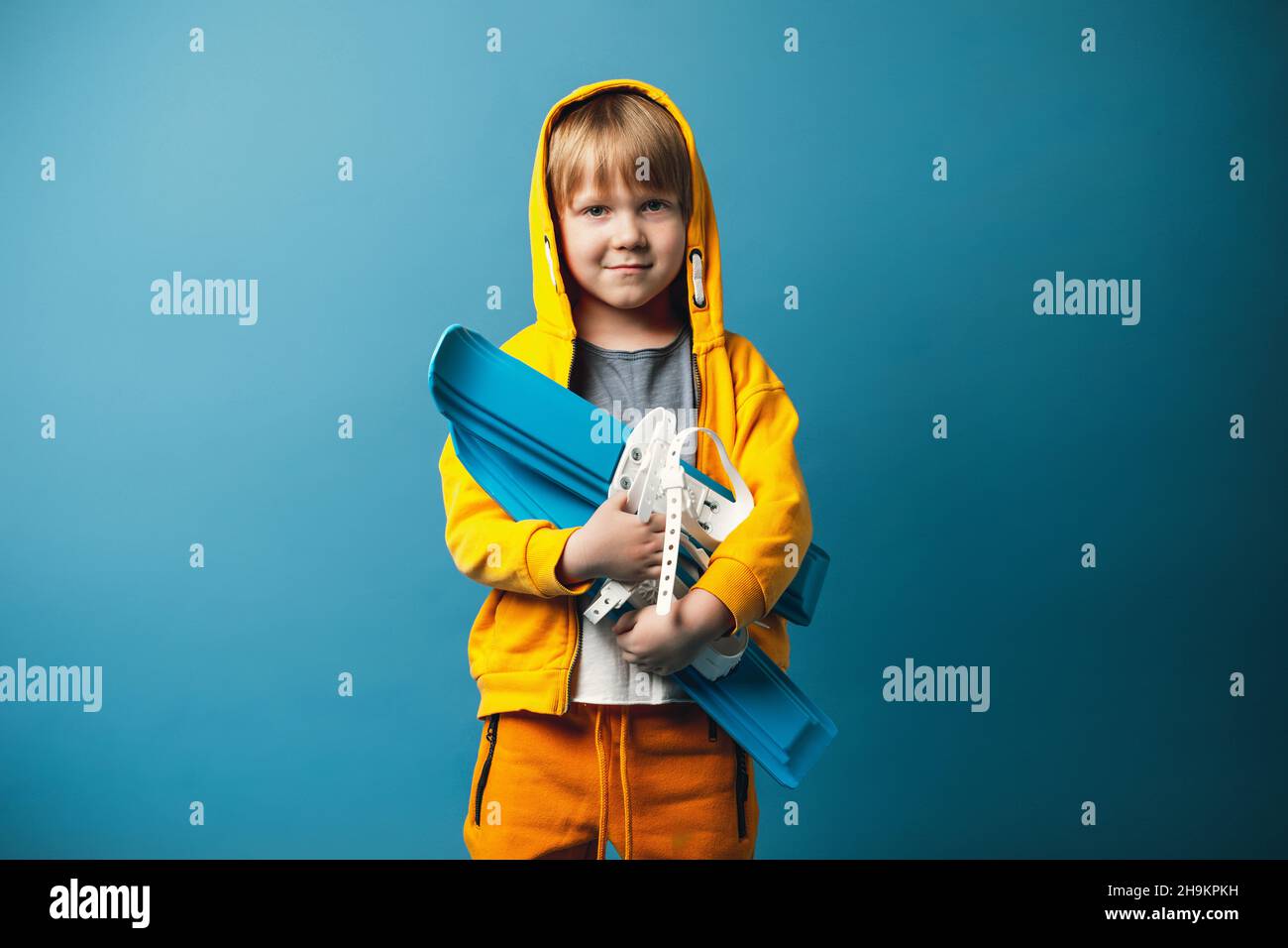 Enfant dans un sweat-shirt jaune avec des skis dans les mains.Concept de loisirs et de sports pour enfants. Banque D'Images