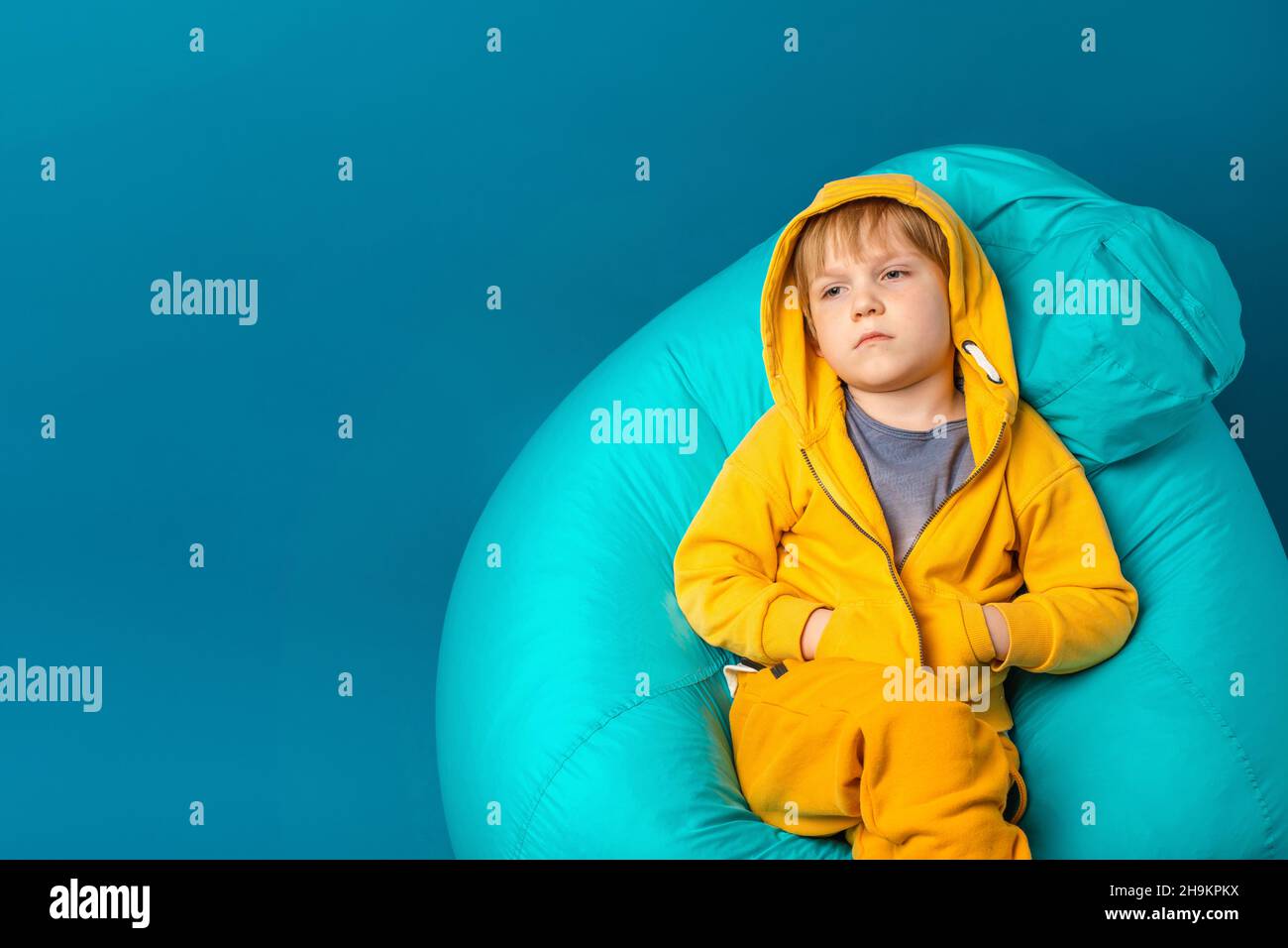 Concept de santé mentale et de dépression chez les écoliers et les enfants d'âge préscolaire.Enfant tout-petit triste et apathie assis sur un sac de haricots. Banque D'Images