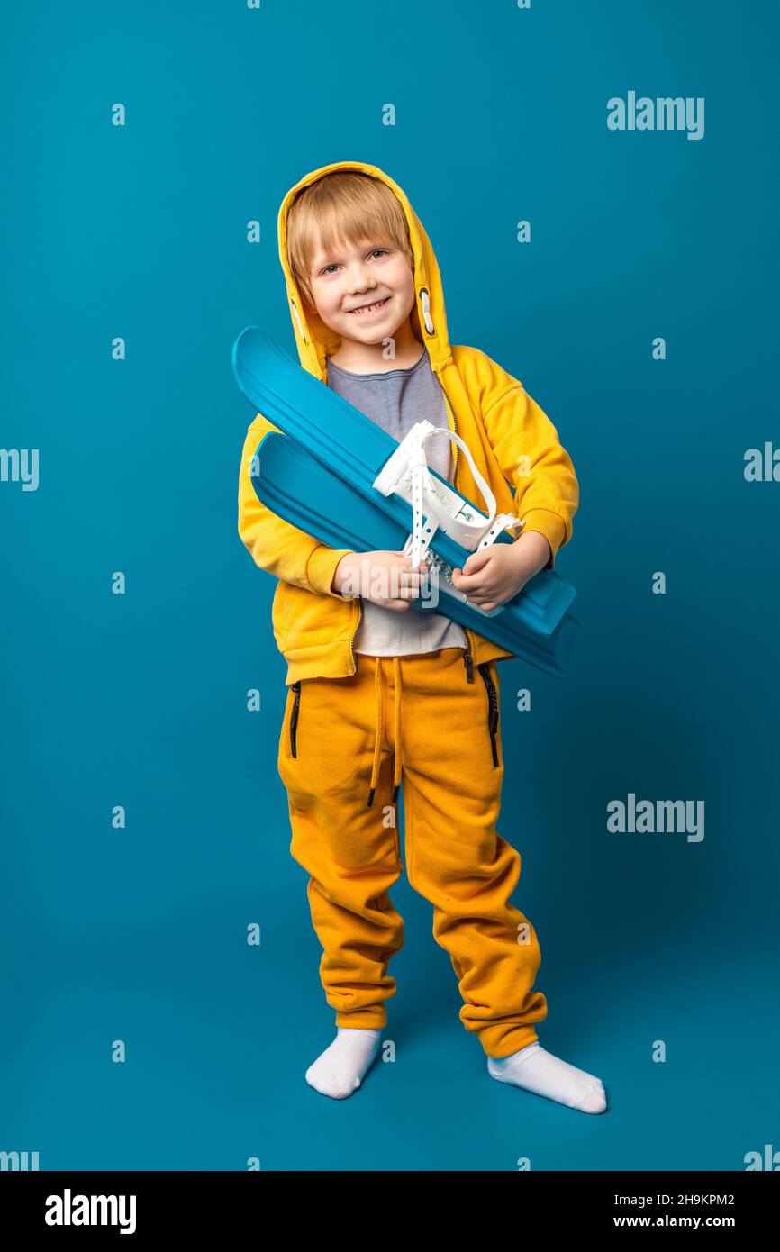 Un enfant dans un sweat-shirt jaune avec des skis dans les mains.Concept de loisirs et de sports pour enfants, prise de vue verticale. Banque D'Images