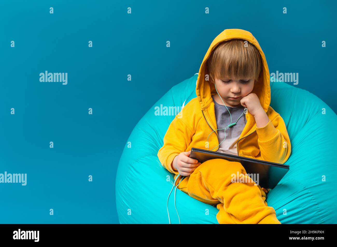Concept de loisirs pour enfants, enfance technologique numérique.PC portable, ordinateur, tablette.Écoutez de la musique avec un casque. Banque D'Images