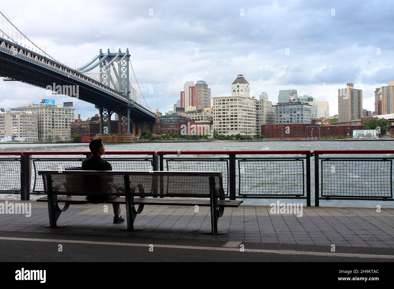 Une personne assise sur un banc qui regarde la rivière East et le quartier DUMBO à Brooklyn, New York.28 août 2011 Banque D'Images
