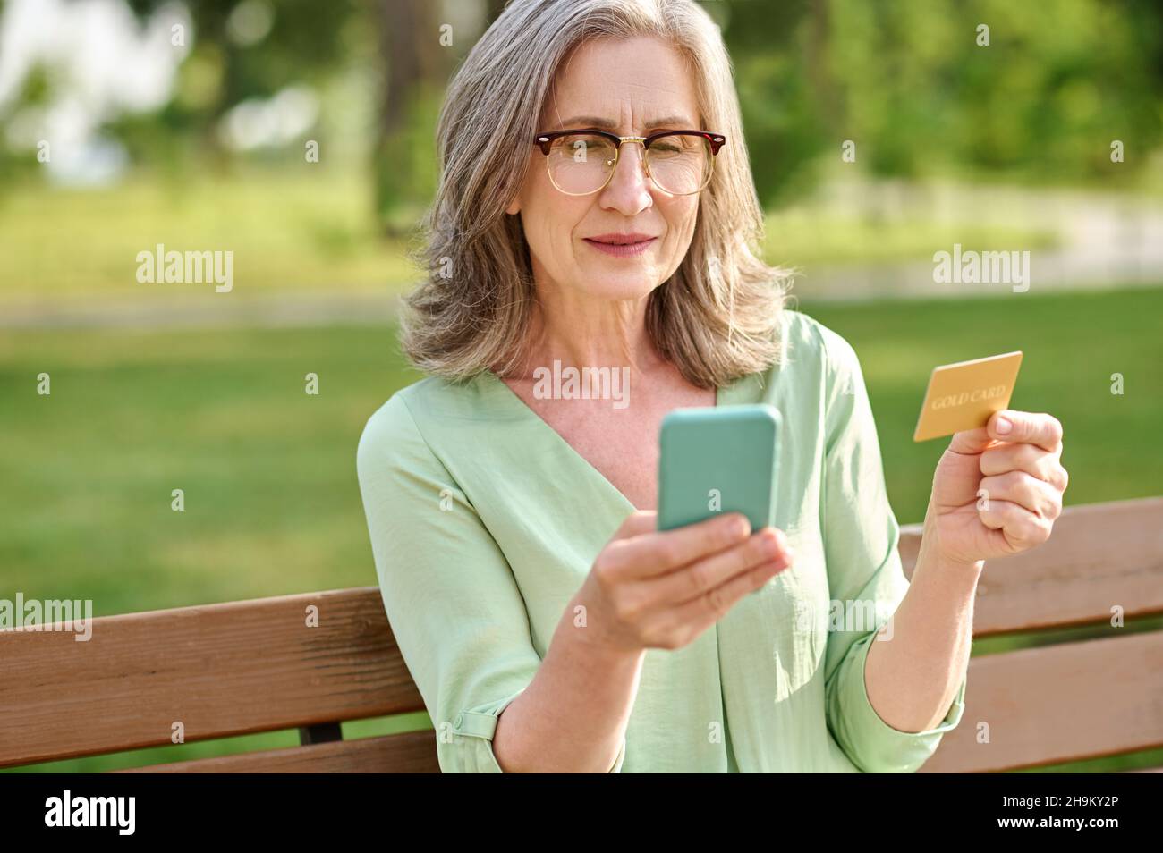 Femme avec carte de crédit regardant l'écran de smartphone Banque D'Images