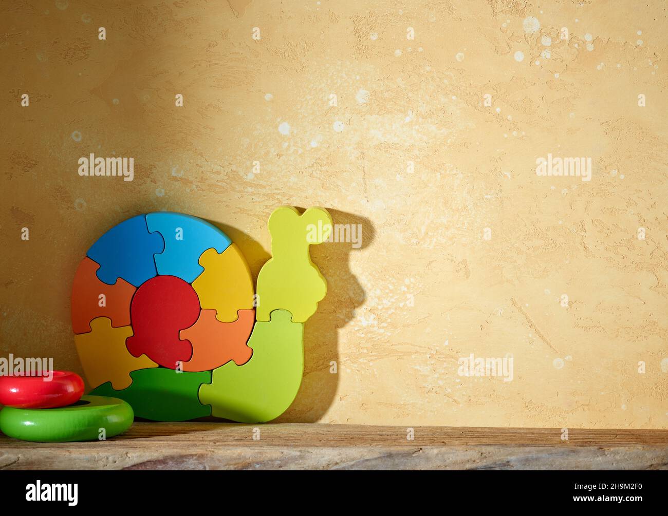 jouets en bois colorés sur étagère et fond de mur jaune Banque D'Images