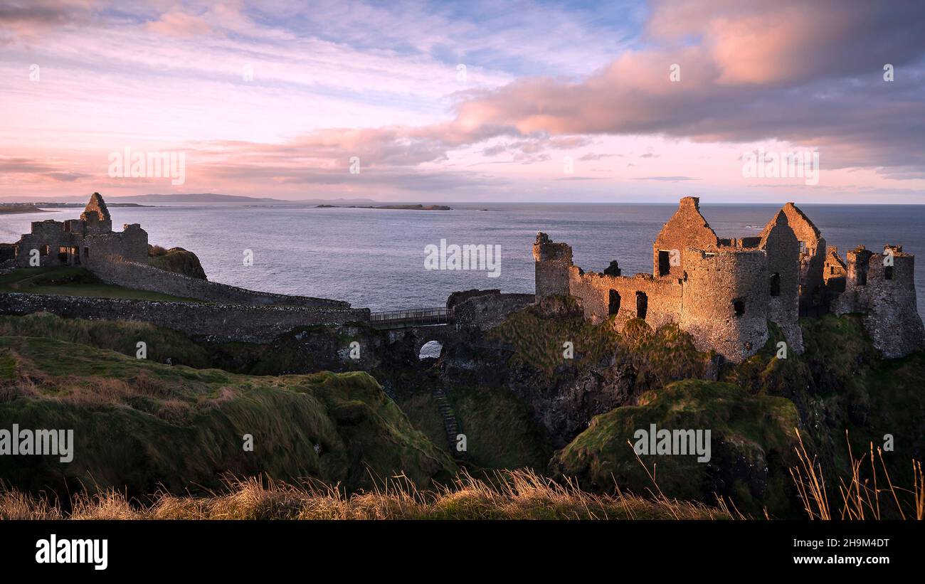 Les ruines emblématiques du château de Dunluce perchées sur un éperon rocheux de la côte nord d'Antrim en Irlande du Nord. Banque D'Images