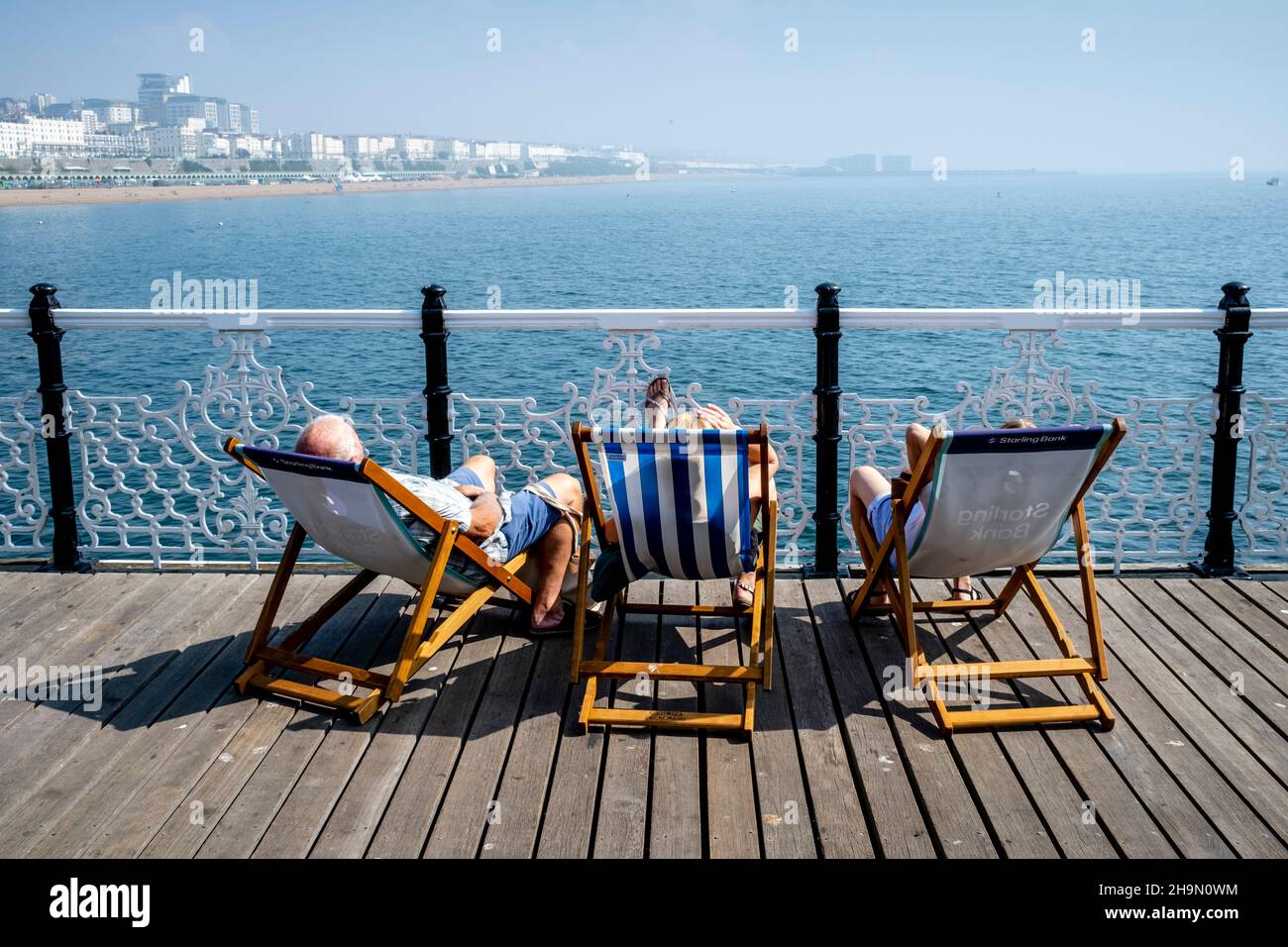 Personnes assises dans des chaises longues sur Brighton Palace Pier lors D'Une journée chaude de Summers, Brighton, Sussex, Royaume-Uni. Banque D'Images
