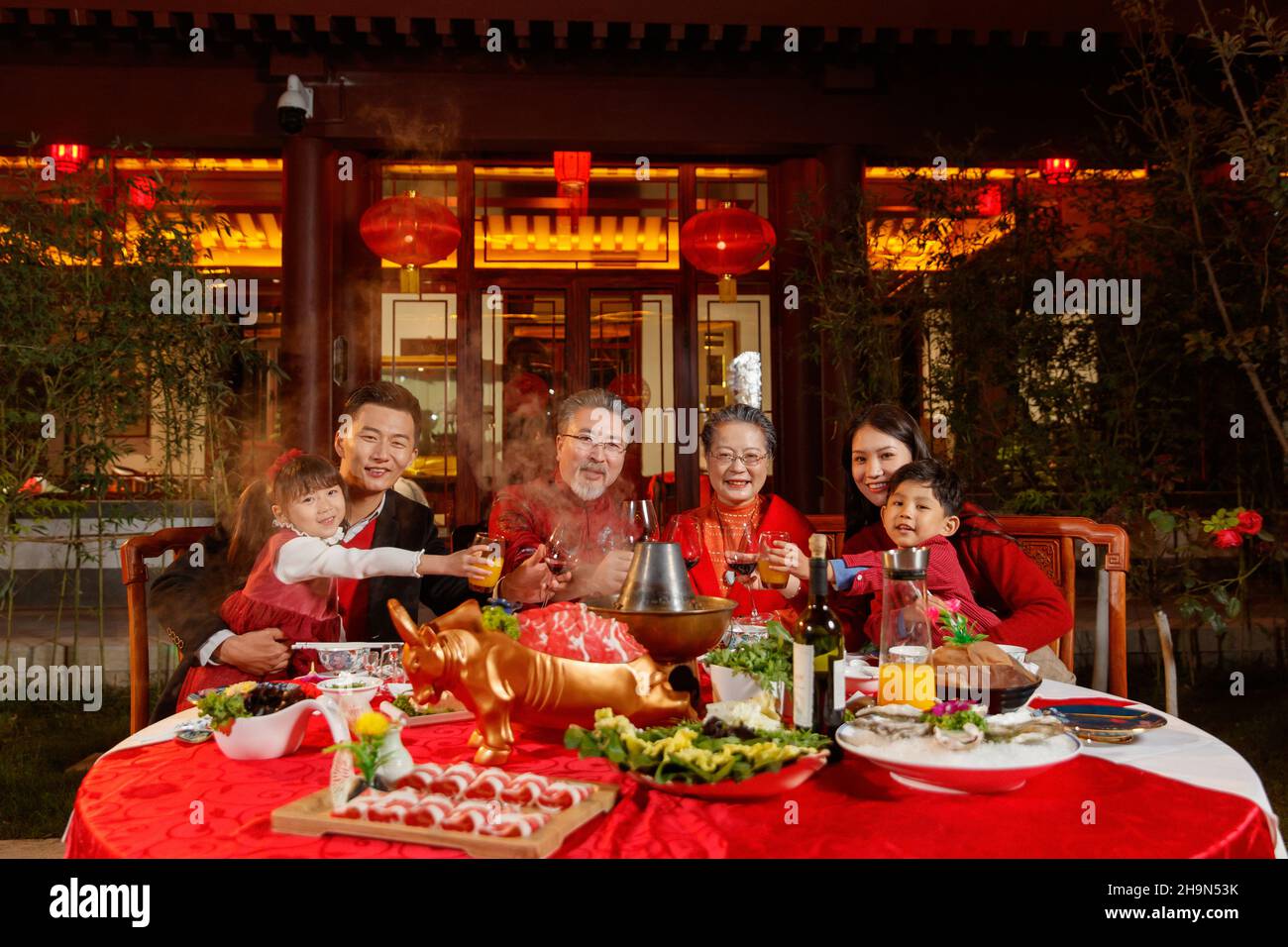 La famille orientale boit un toast pour célébrer le nouvel an dans le jardin chinois Banque D'Images