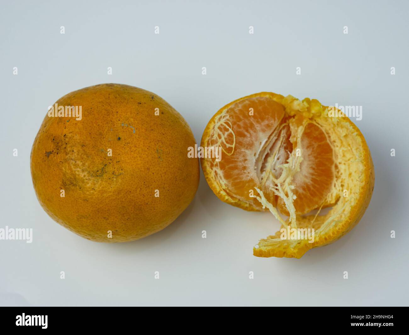 deux oranges, dont une pelée sur fond blanc. concept de fruits sains Banque D'Images