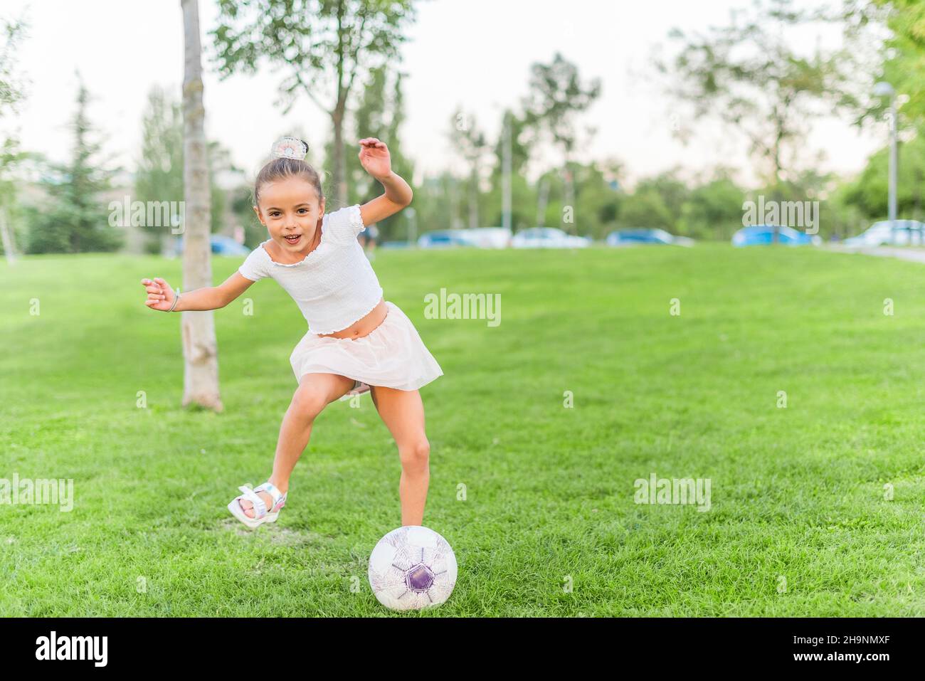 Une petite fille jouant avec le ballon de football au parc Banque D'Images