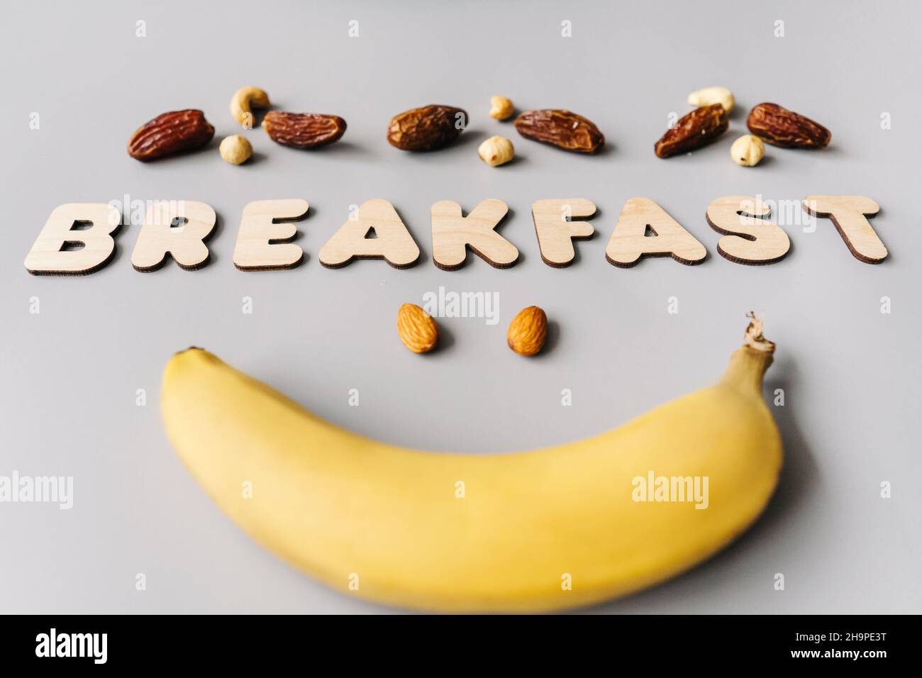 Petit déjeuner lumineux sur fond gris.Banane et noix avec petit déjeuner mot.Concept végétarien. Banque D'Images