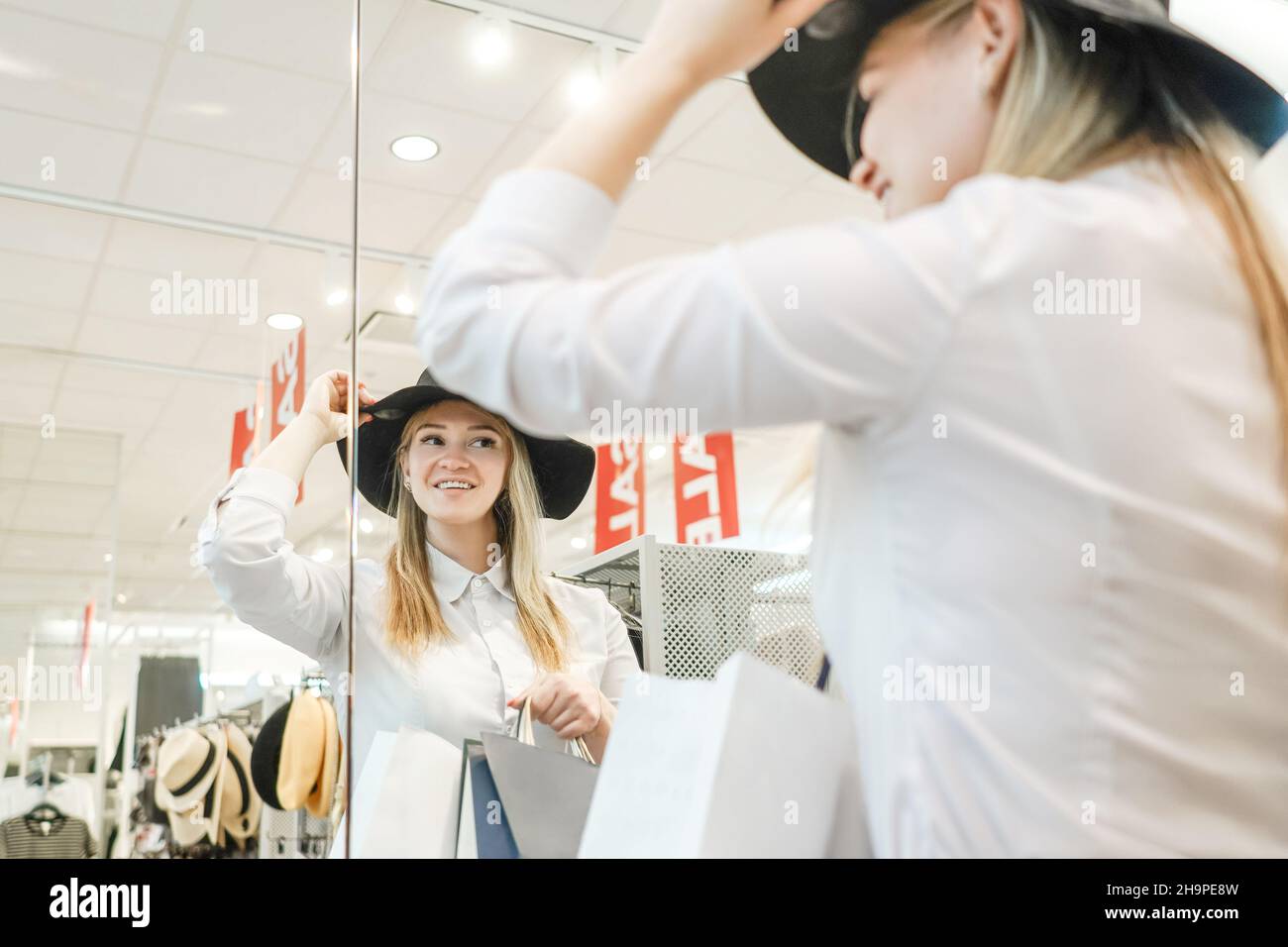 une femme dans un magasin essaie un chapeau et regarde dans le miroir. Banque D'Images